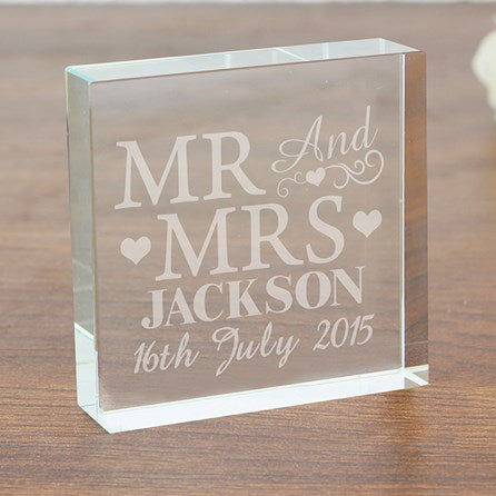 Clear glass block with engraved 'MR AND MRS JACKSON' and date on a wooden surface