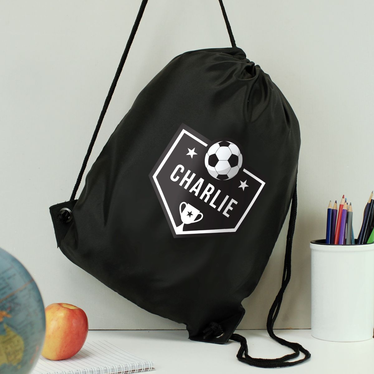 Black drawstring bag with 'CHARLIE' and soccer ball design on a light gray background