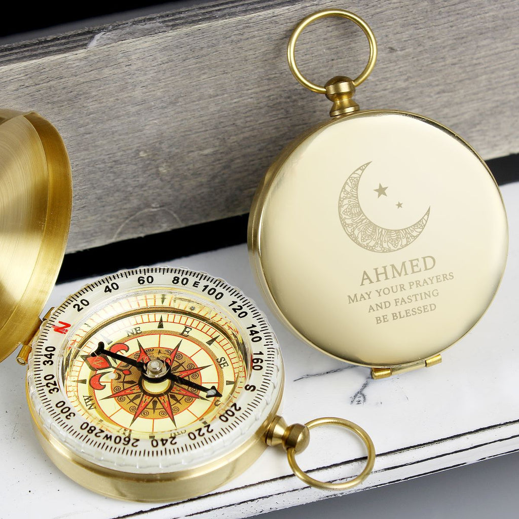 Gold compass with engraved text on a wooden surface