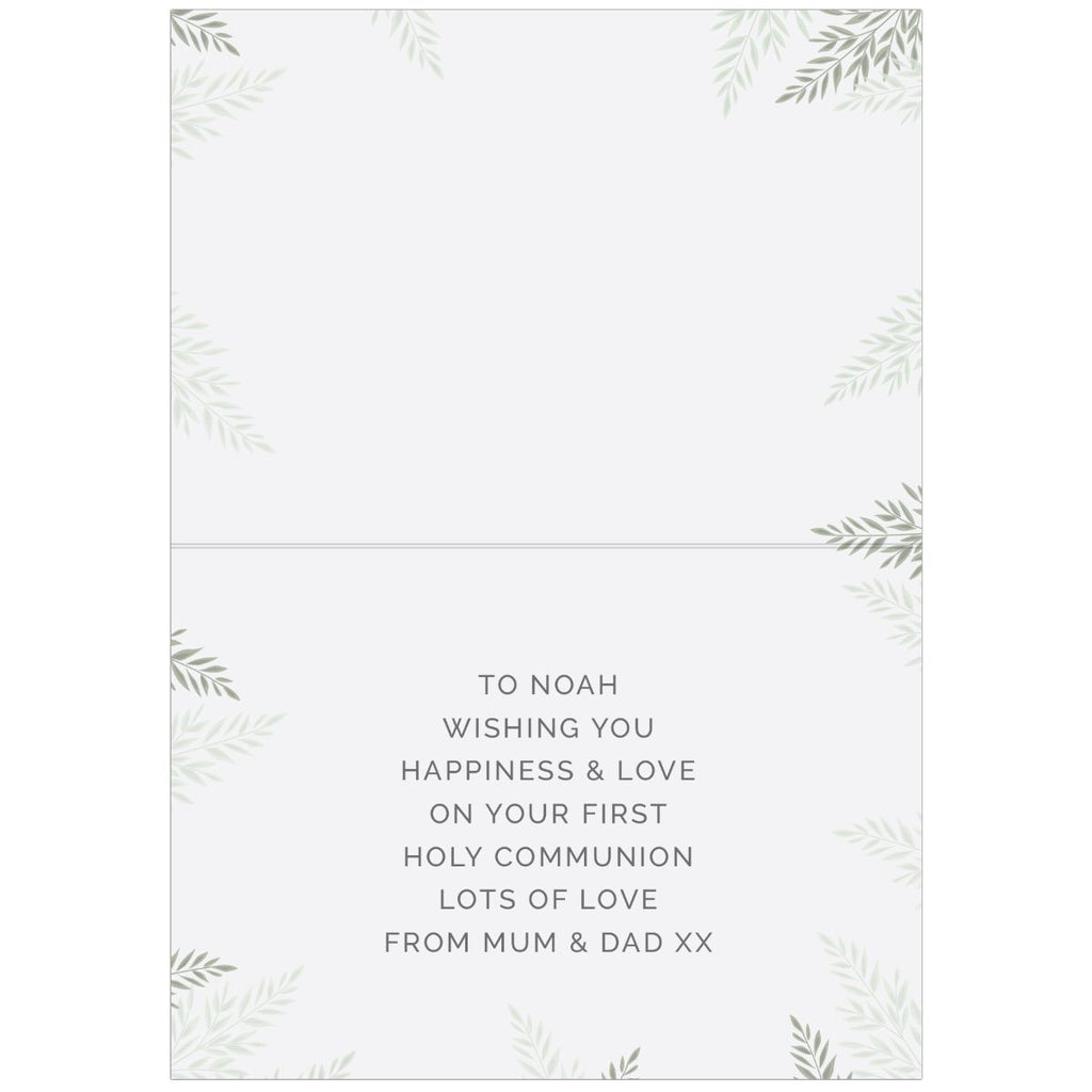 A folded greeting card with a white background, featuring a delicate green leaf border design and printed text that reads: 'TO NOAH WISHING YOU HAPPINESS & LOVE ON YOUR FIRST HOLY COMMUNION LOTS OF LOVE FROM MUM & DAD XX'.