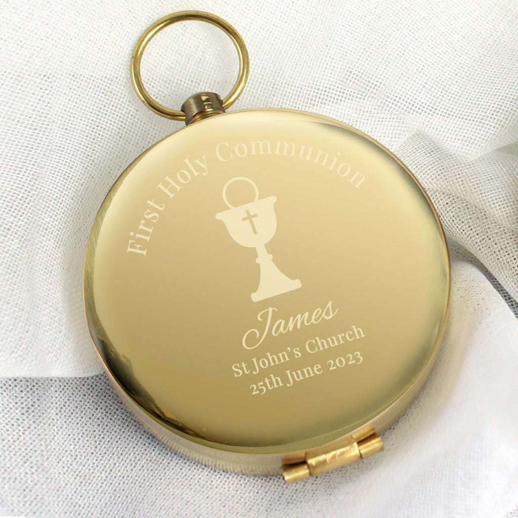 Gold pocket watch with engraved text on a white fabric background
