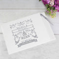 Personalized wedding book with names and date on a light wooden surface with flowers.