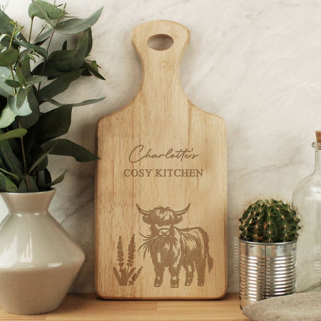 Wooden cutting board with engraved design and text, placed on a surface with plants and decor.