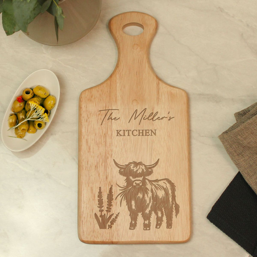 Wooden cutting board with engraved cow design and 'The Miller's Kitchen' text on a light surface.