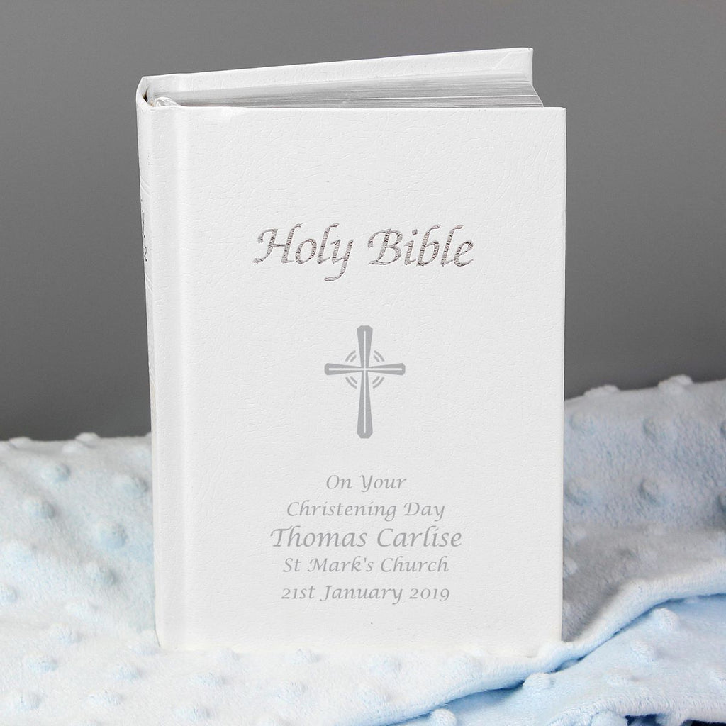 White Bible with engraved text and cross design on a soft fabric background
