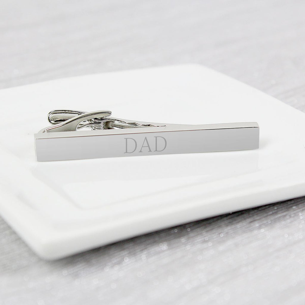 Silver tie clip with 'DAD' engraving on a white marble surface