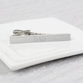Silver tie clip with 'DAD' engraving on a white marble surface