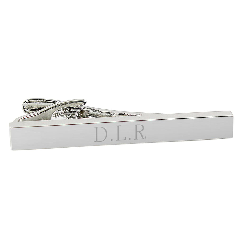 Silver tie clip with letters engraved.