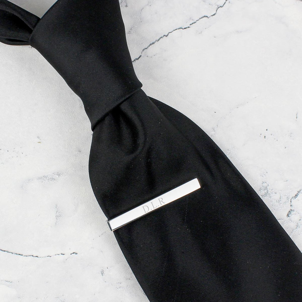 Black tie with a silver clasp on a marble surface