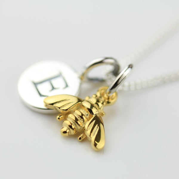 Gold bee charm on a silver chain against a white background