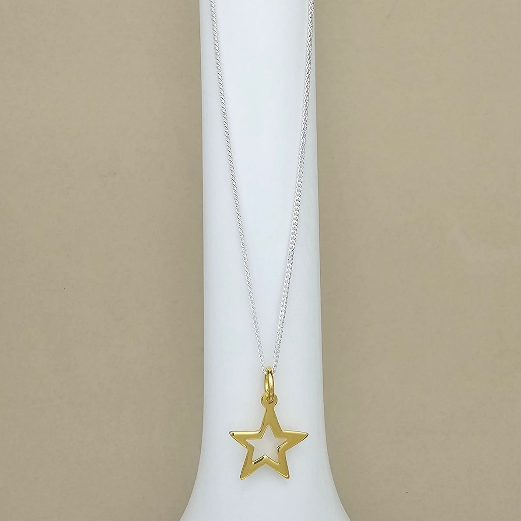 A gold star-shaped pendant necklace on a delicate silver chain, displayed on a white jewelry bust against a neutral beige background.