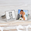 A pair of square silver-toned cufflinks displayed on a light wood surface. One cufflink shows personalised black text on a white background reading '08 08 20 MARTIN & PATRICIA', the other cufflink displays a photo.