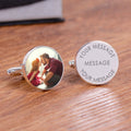 A pair of round silver cufflinks engraved with personalised wording and photo, one reading 'YOUR MESSAGE' and the other a photo, displayed on a wooden surface.