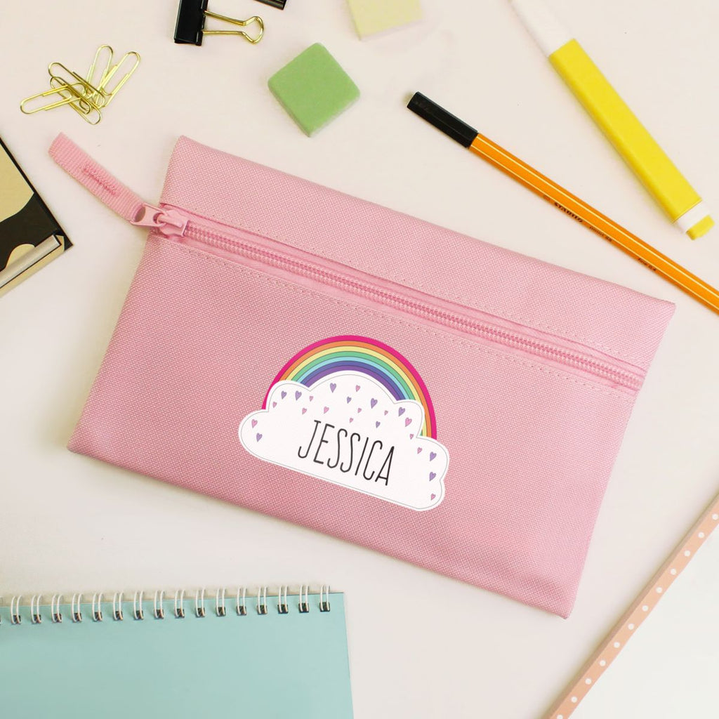 Pink pencil case with rainbow and cloud design, personalized with name 'Jessica', on a desk with stationery items.