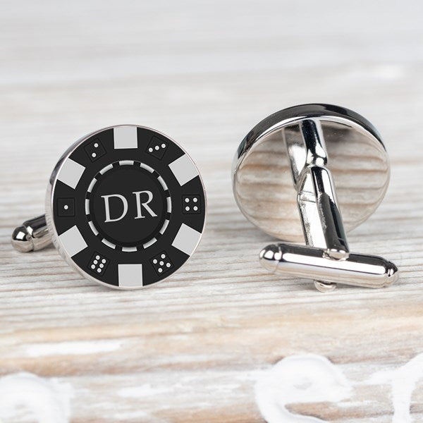 A pair of round silver-toned cufflinks styled like black and white casino chips. One cufflink is shown from the front with a black center, white border segments, and the initials 'DR' in white.