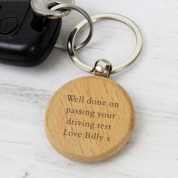 Wooden keychain with engraved message on a light wooden surface