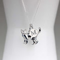 A silver necklace with a cat-shaped pendant and a circular charm engraved with the letter 'M', displayed on a white mannequin bust.