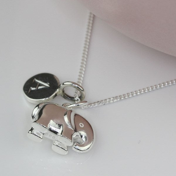 A silver elephant pendant necklace with a matching round initial 'A' charm, displayed on a light gray surface.