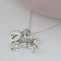 Silver necklace with horse pendant and circular charm on a white background