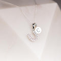 Silver horseshoe necklace with a letter 'S' pendant on a white background