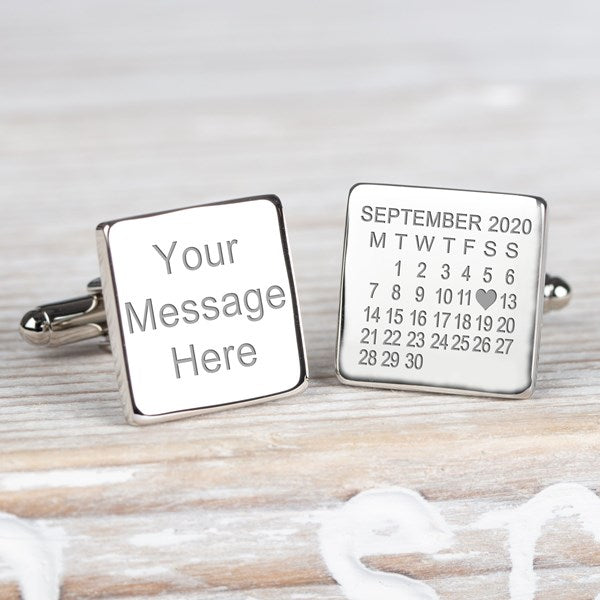 A pair of square silver cufflinks displayed on a light grey surface. One cufflink is engraved with the words 'Your message here' and the other shows a September 2020 calendar with 12th day as heart symbol.