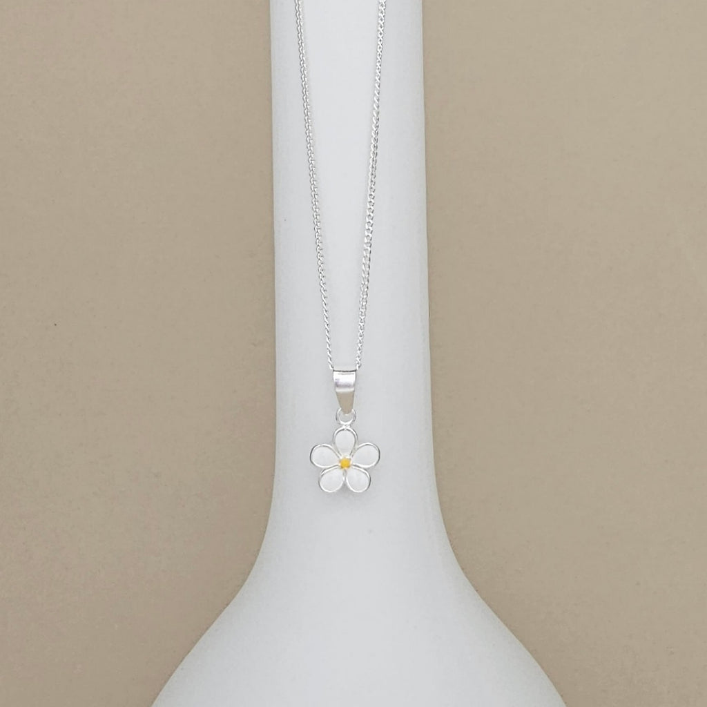 A silver flower pendant necklace with a small yellow center, displayed on a white neck mannequin against a beige background.
