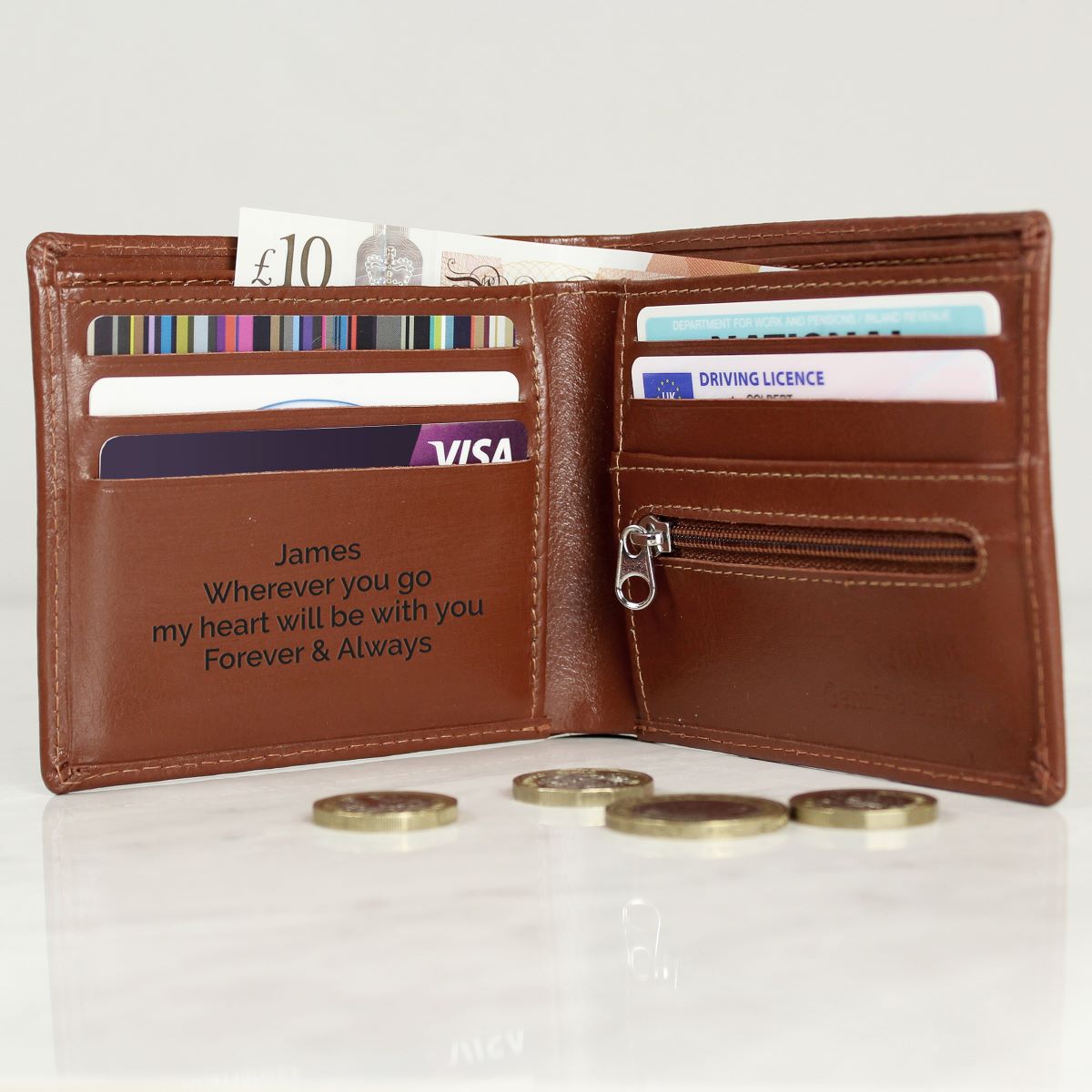Brown leather wallet with engraved message, cards, and coins on a white background