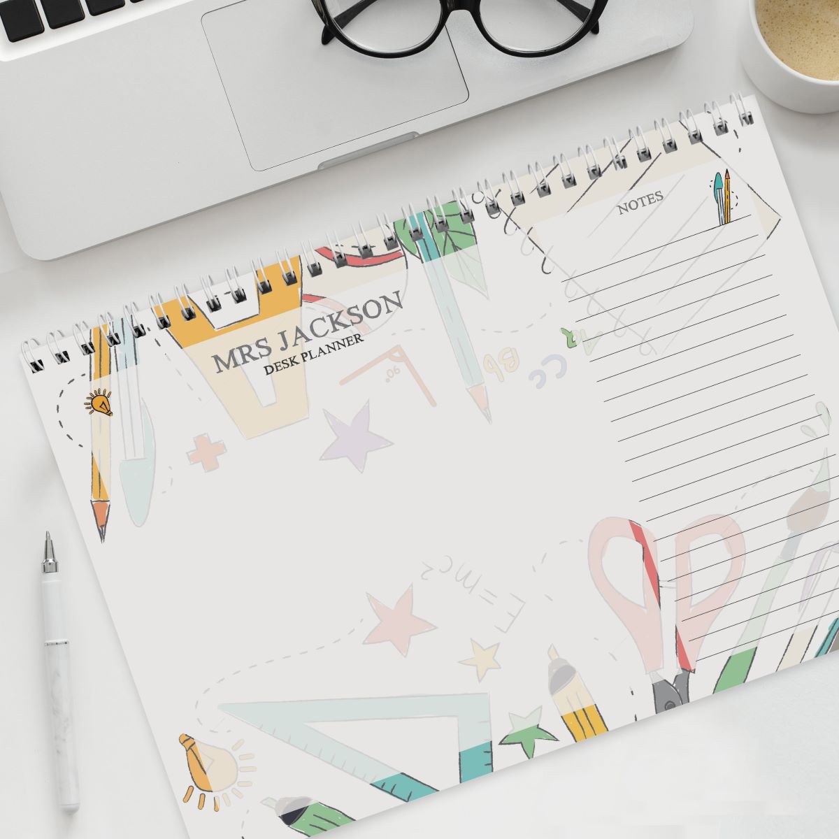 Desk planner with colorful design on a desk with a laptop and glasses.