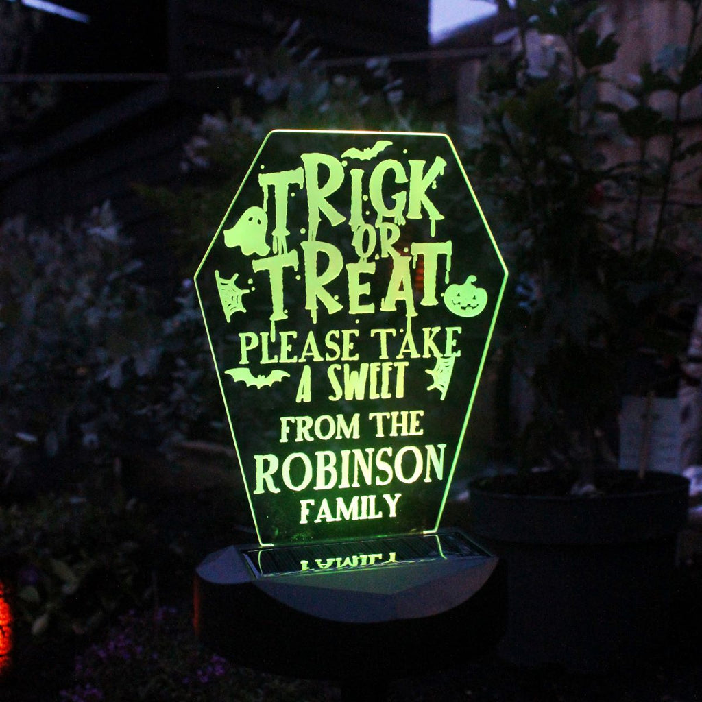 Glowing Halloween-themed sign with personalized text in a dark outdoor setting.