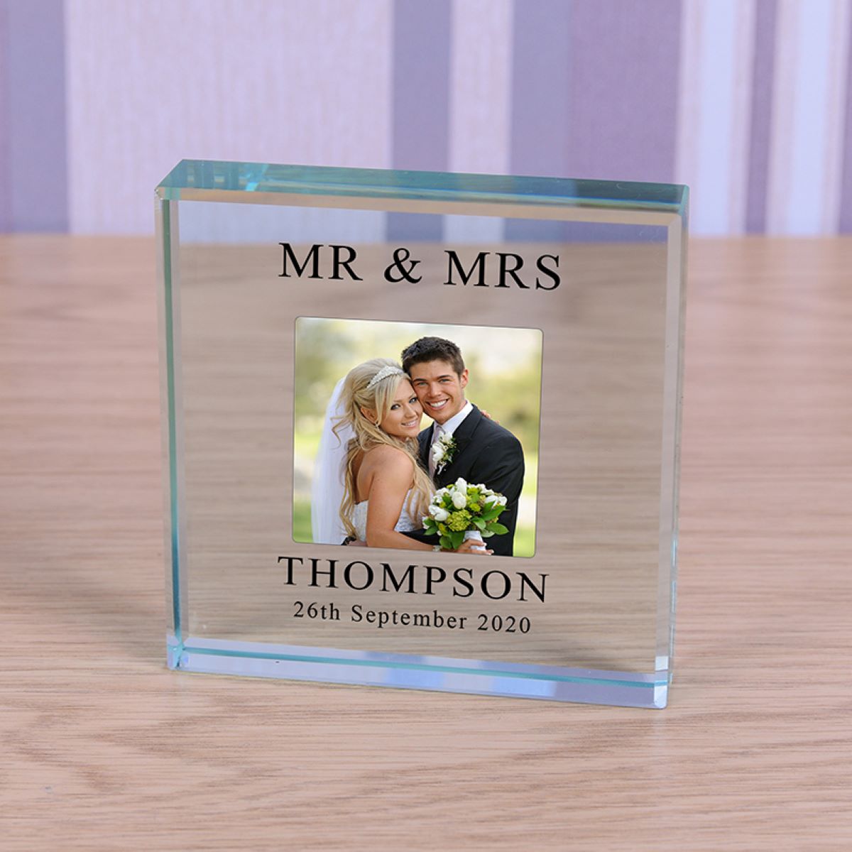 Glass photo block with a wedding photo and the text 'Mr & Mrs Thompson 26th September 2020' on a wooden surface