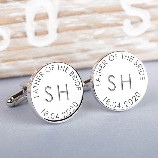 A pair of round silver cufflinks engraved with 'FATHER OF THE BRIDE', the initials 'SH', and the date '18.042020'.