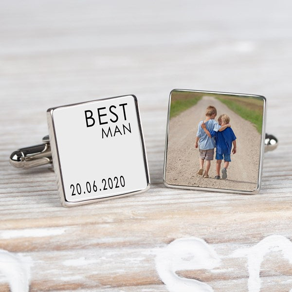 A pair of square silver cufflinks on a whitewashed wooden surface. One cufflink is engraved with the name 'BEST MAN' and the date '20.06.2020 and the other cufflink a personalised image.