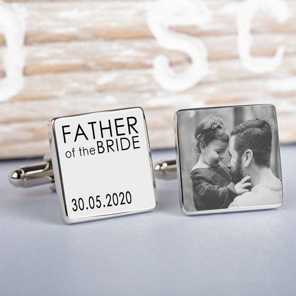 A pair of square silver cufflinks on a whitewashed wooden surface. One cufflink is engraved with the words 'FATHER of the BRIDE' and the date '30.05.2020 and the other cufflink a personalised image.