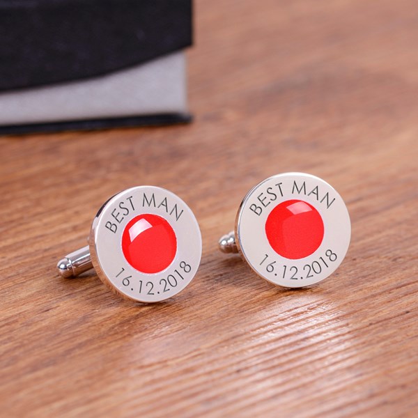 A pair of personalised silver cufflinks with a red circular gem centre and engraved text reading 'BEST MAN' and '16.12.2018'.