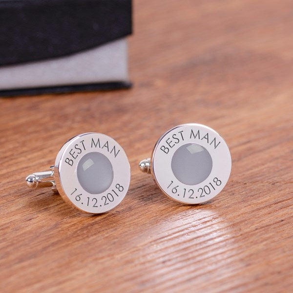 A pair of personalised silver cufflinks with a grey circular gem centre and engraved text reading 'BEST MAN' and '16.12.2018'.