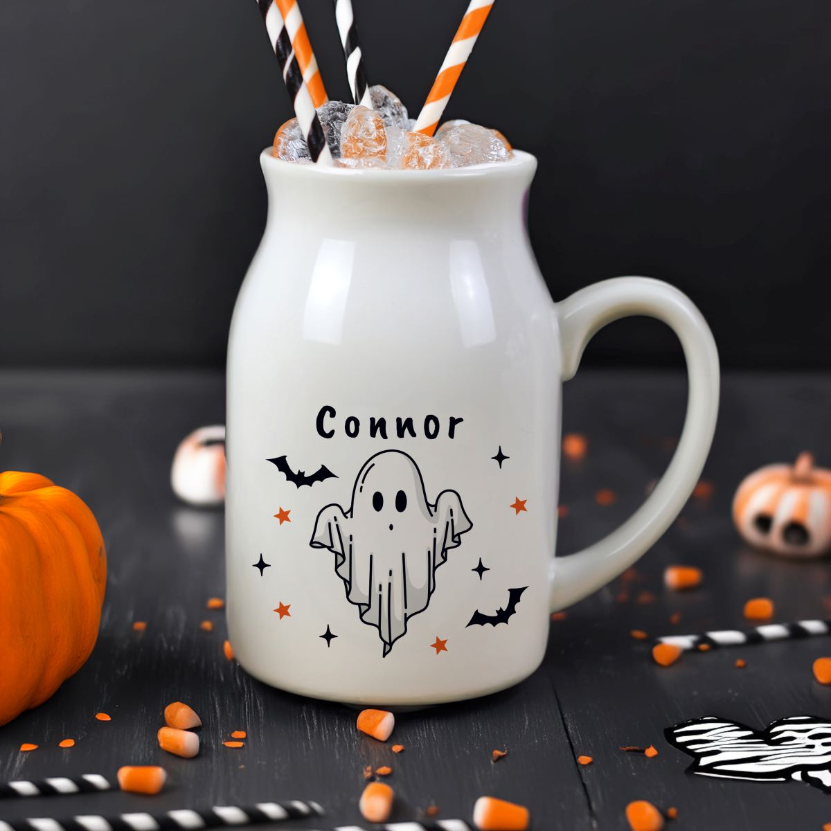 White mug with 'Hannah' and ghost design, filled with Halloween-themed drink on a black background.