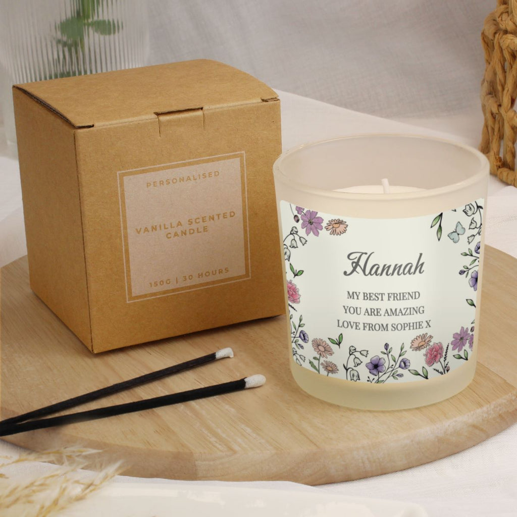 Personalized vanilla scented candle with floral label and packaging on a wooden surface.