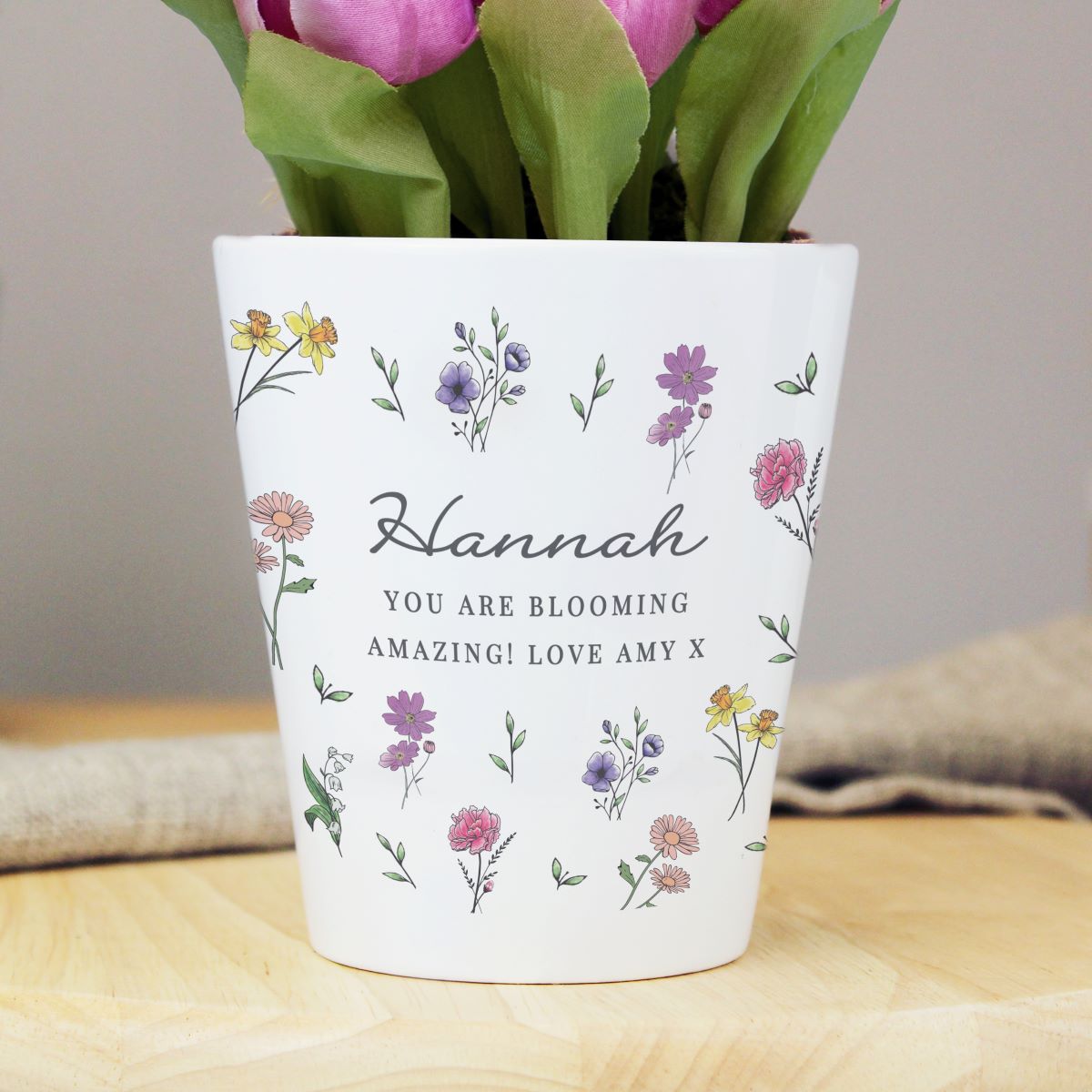 Floral-patterned pot with tulips on a wooden surface