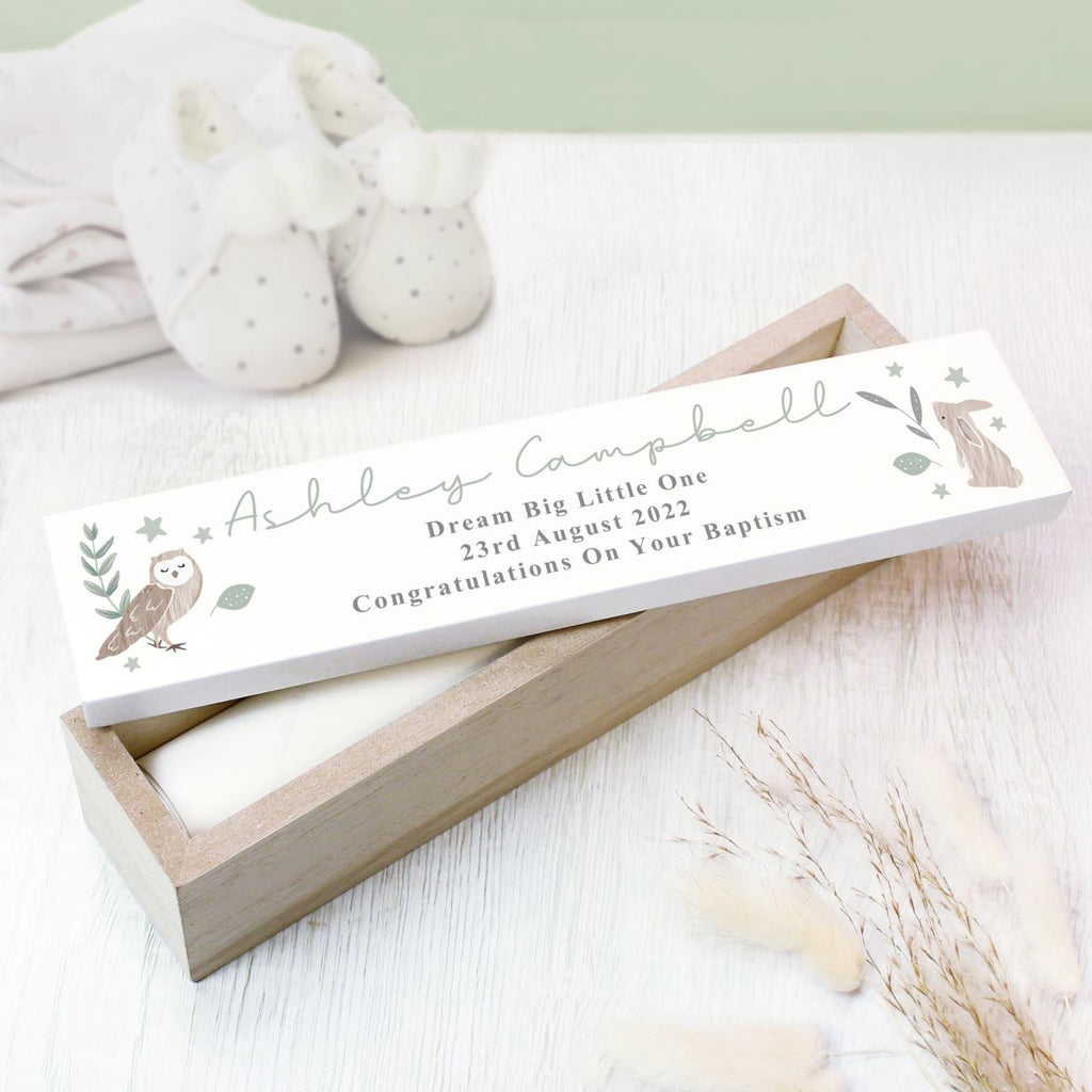Wooden box with a birth announcement card featuring an owl design on a light wooden surface.