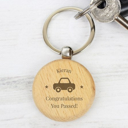 Wooden keychain with engraved text and car illustration on a white background