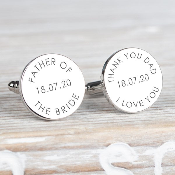 A pair of round silver cufflinks engraved with personalised wedding text, including 'FATHER OF THE BRIDE' and 'THANK YOU DAD I LOVE YOU' with a date.