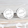 A pair of round silver cufflinks engraved with personalised wedding text, including 'FATHER OF THE BRIDE' and 'THANK YOU DAD I LOVE YOU' with a date.