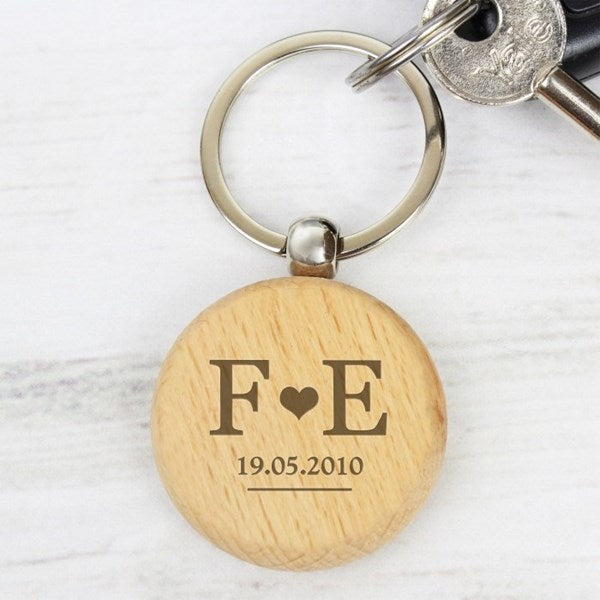 A personalized round wooden keychain with engraved initials 'F♥E' and the date '19.05.