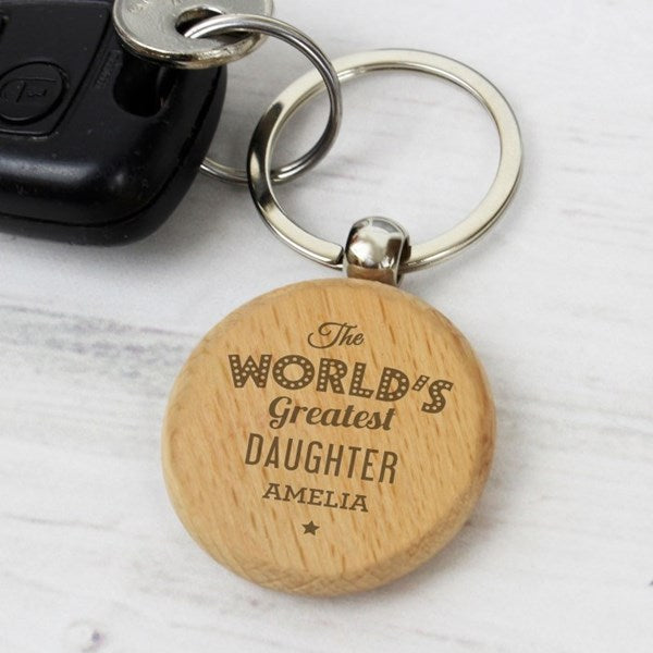 Wooden keychain with 'The World's Greatest Daughter Amelia' engraving on a light wooden surface.