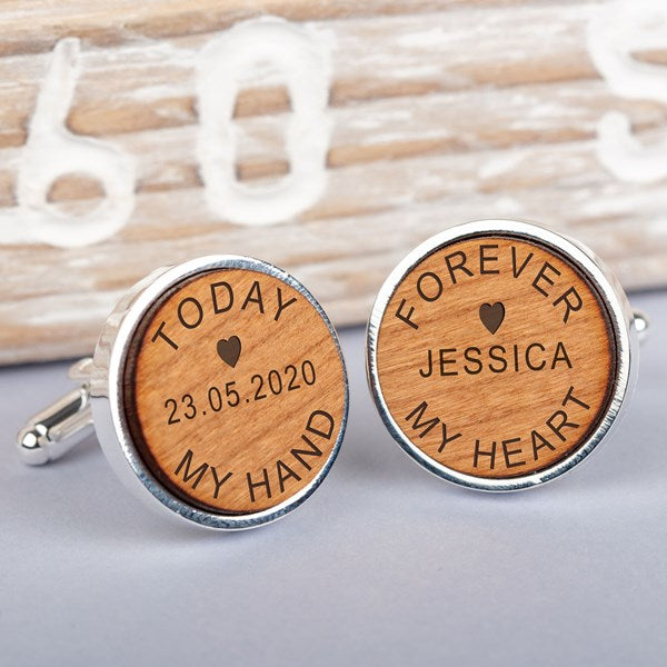 A pair of round silver cufflinks with engraved light brown wooden faces. One cufflink is engraved with 'TODAY 23.05.2020 MY HAND' and the other 'FOREVER JESSICA MY HEART'