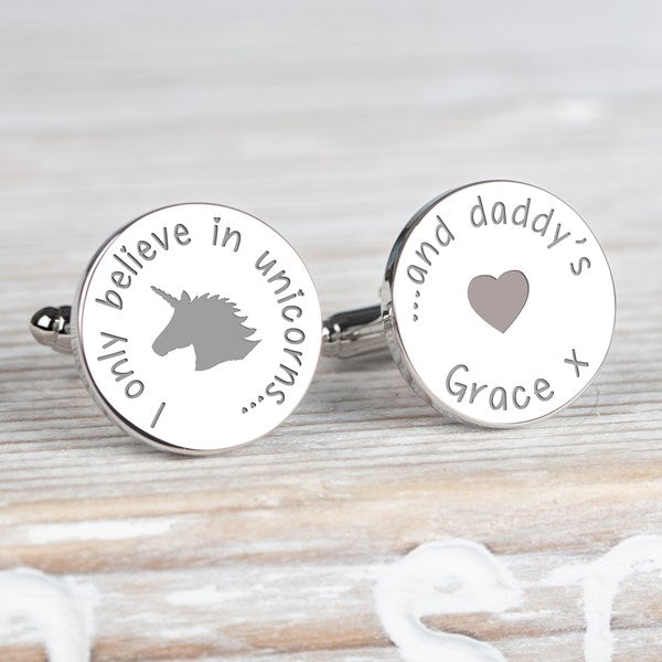 A pair of round silver cufflinks with engraved custom text and designs. One cufflink features a grey unicorn silhouette and the phrase 'I only believe in unicorns, and the other cufflink  '... and daddy's' and a heart silhouette and the name Grace.