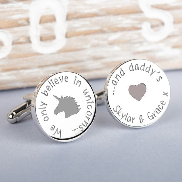 A pair of round silver cufflinks with engraved custom text and designs. One cufflink features a grey unicorn silhouette and the phrase 'We only believe in unicorns, and the other cufflink  '... and daddy's' and a heart silhouette and the names Skylar and Grace.
