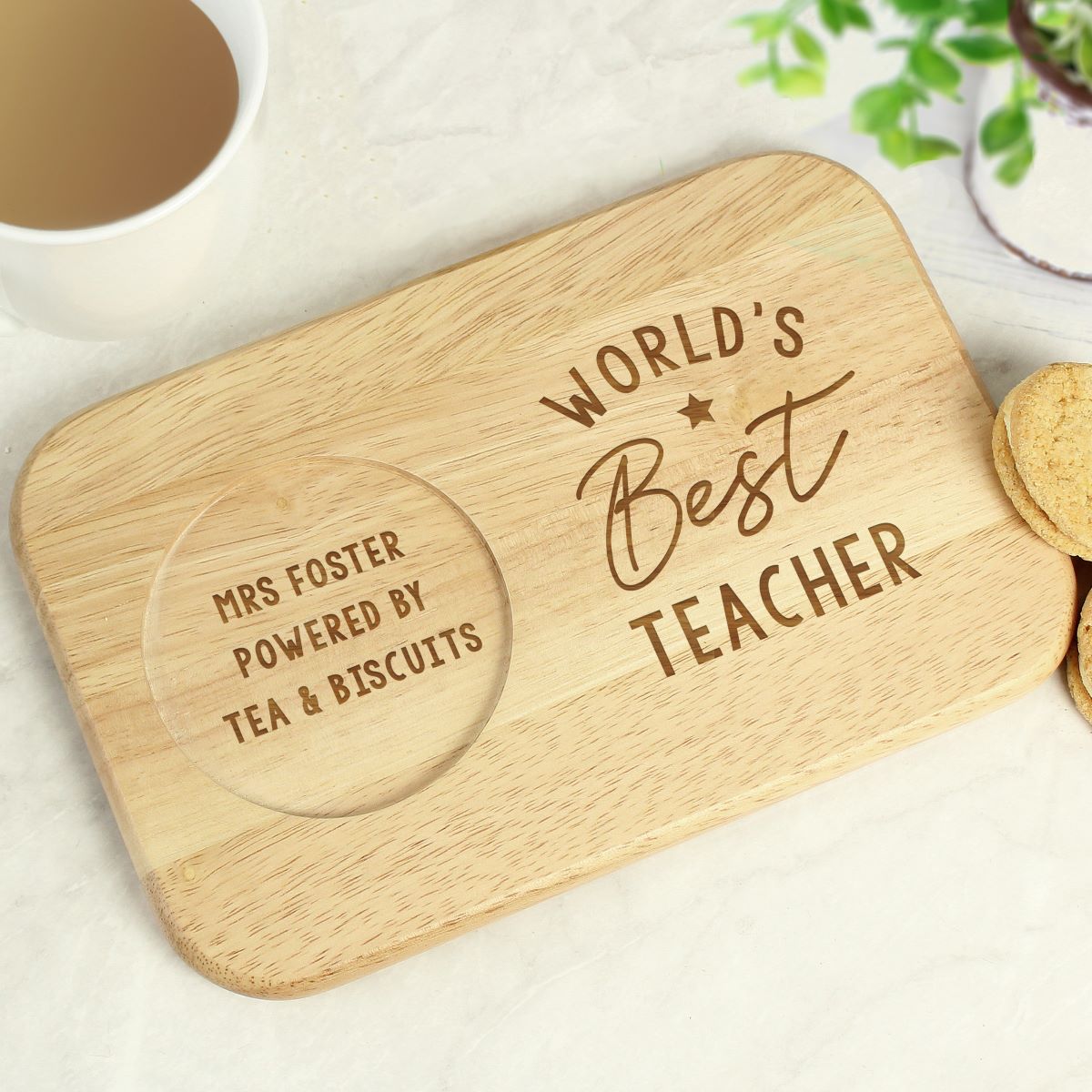 Wooden coaster with 'World's Best Teacher' and 'Powered by Tea & Biscuits' text on a light surface.