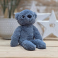 A blue soft fuzzy plush teddy bear toy, with black eyes and nose, on a wooden surface with a blurred star-shaped object in the background
