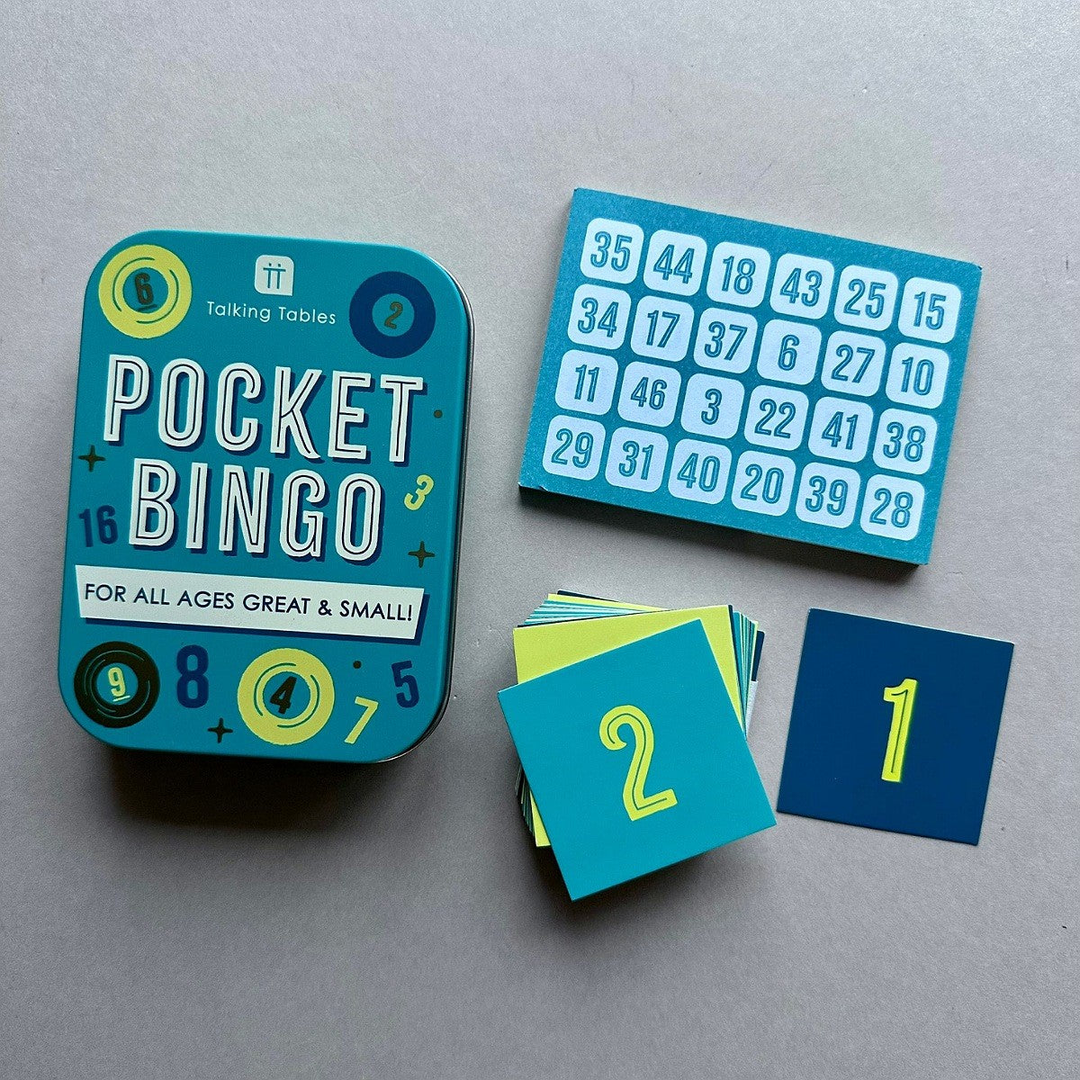 Pocket Bingo game set on a neutral grey background, featuring a teal tin box, a blue bingo card with numbered squares, and several blue and yellow bingo tiles.